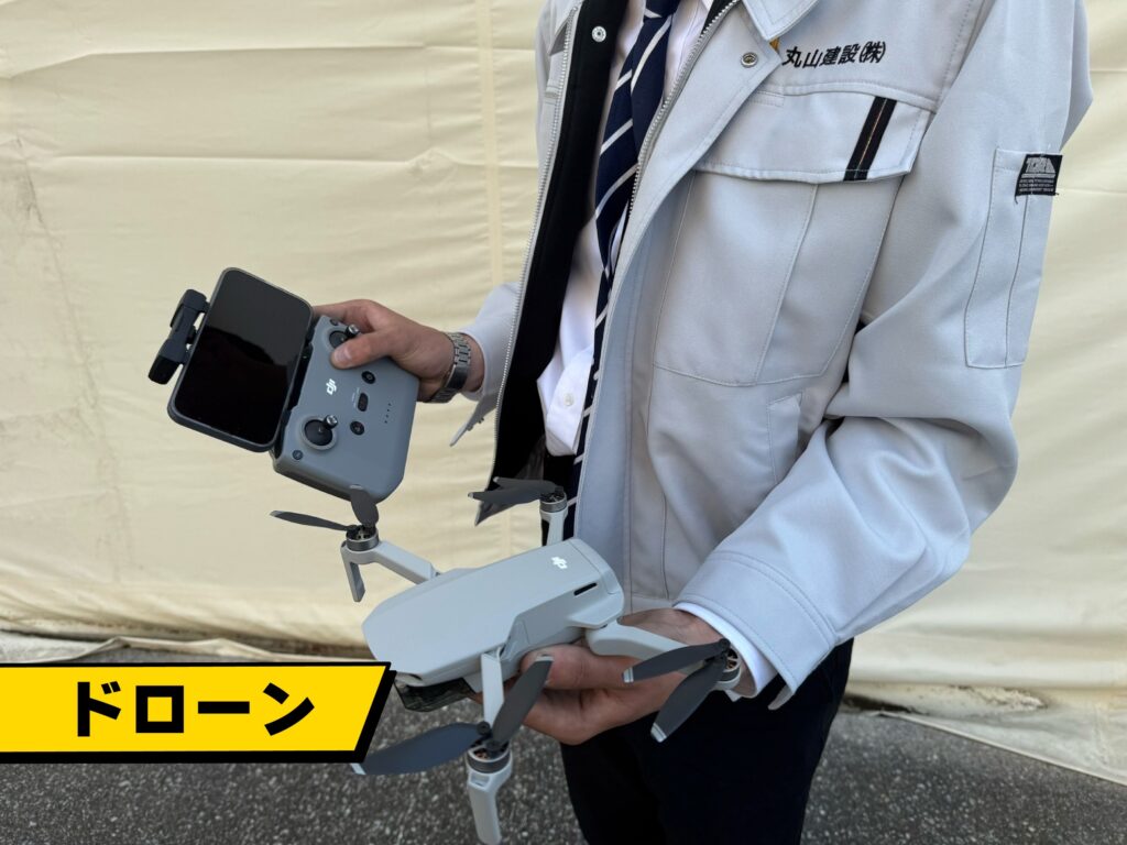 丸山建設株式会社のドローンを営業部長の中野大和が手に持っている様子