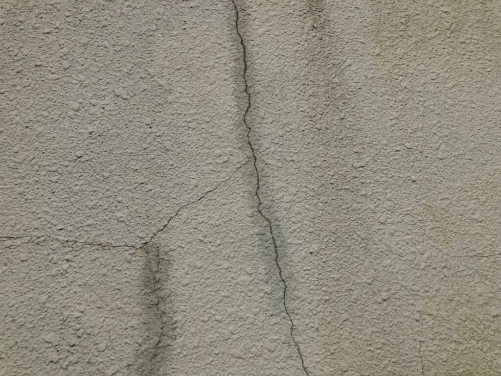 地震の影響により外壁表面にひび割れが広がり、劣化が進行している状況