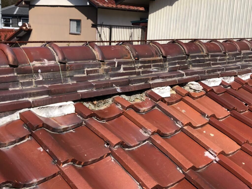 棟の漆喰が崩れて内部が露出した瓦屋根の破損状態