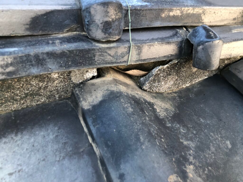 棟の漆喰が崩れて内部が露出した瓦屋根の破損状態