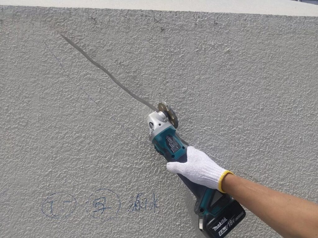 外壁のひび割れをサンダーでVカットしている写真
