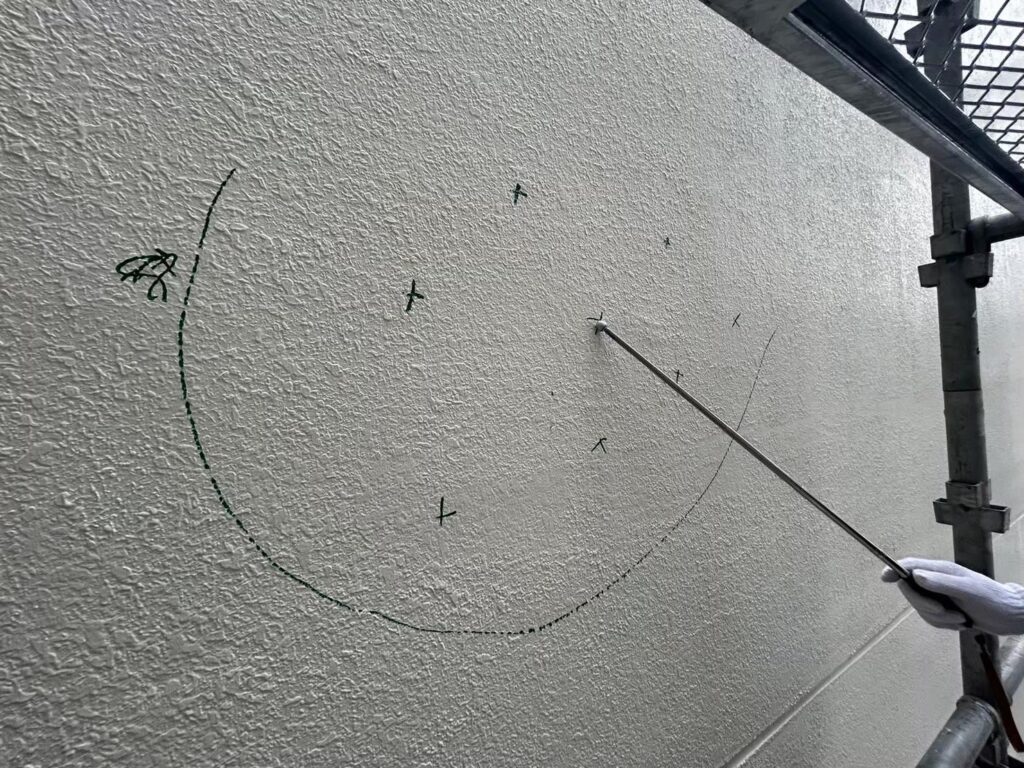 打診棒で外壁を調査している写真