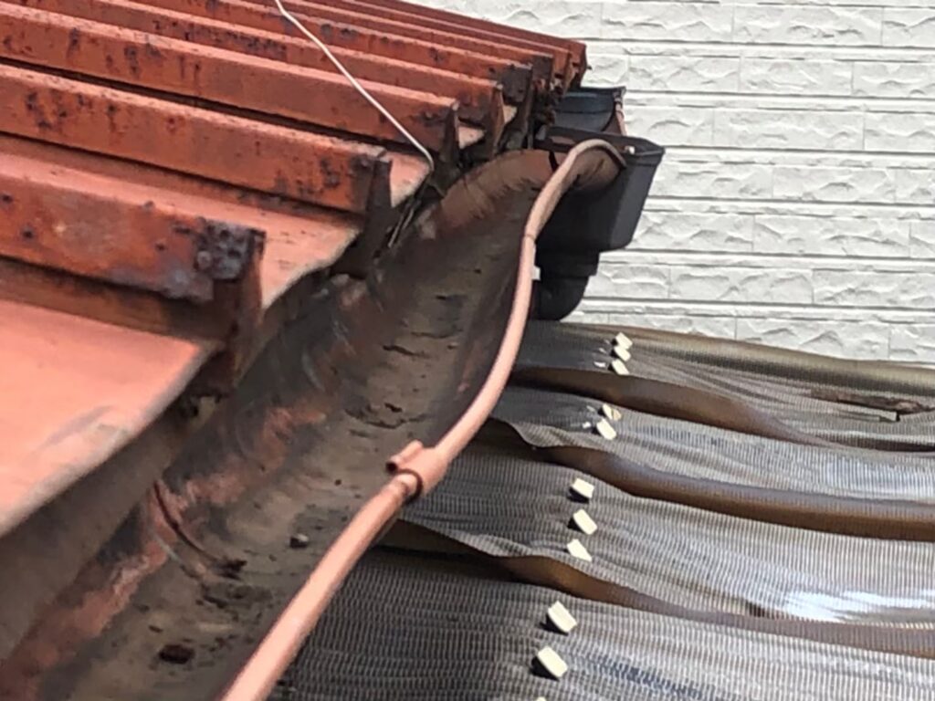 強風の影響により雨樋が大きく歪んでいる状態