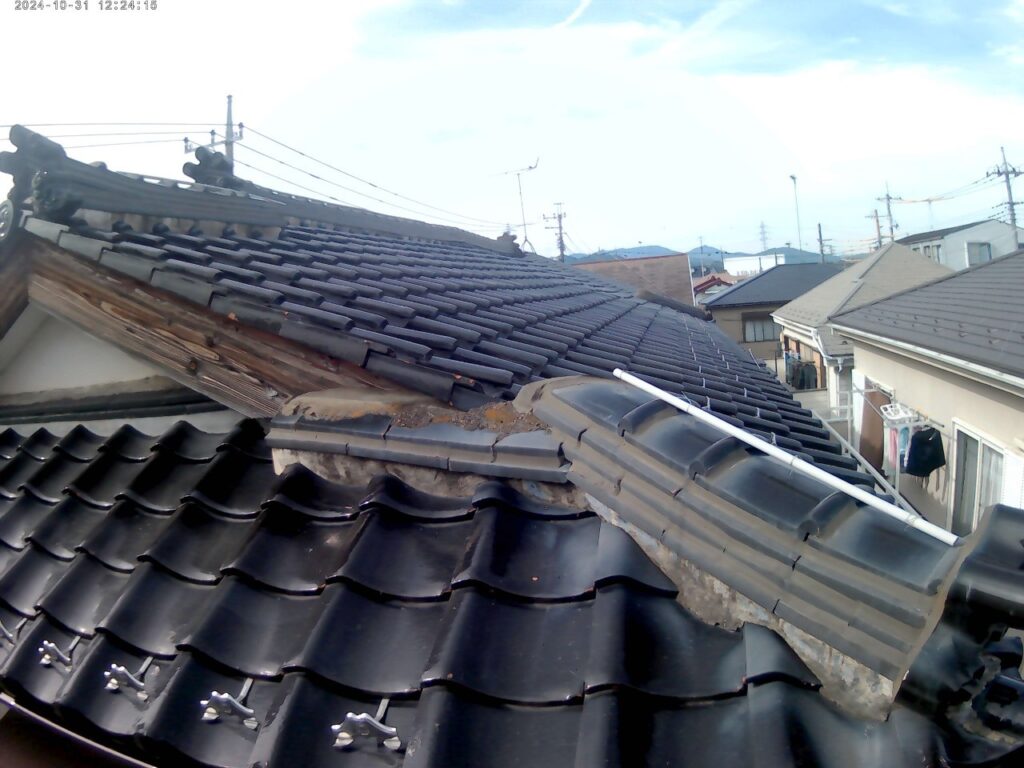 瓦屋根の棟部分で漆喰が腐食し、黒ずみや欠損が確認できる様子