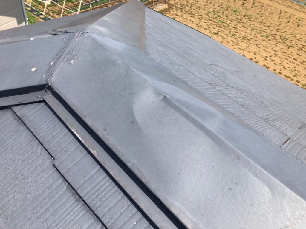 棟板金が強風や飛来物の衝撃でへこみ、形状が変わってしまっている様子