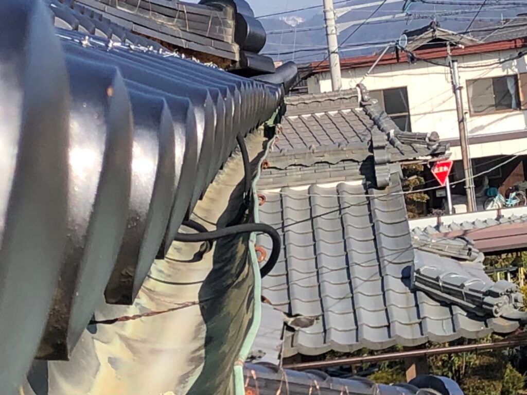 強風の影響により雨樋が大きく歪んでいる状態