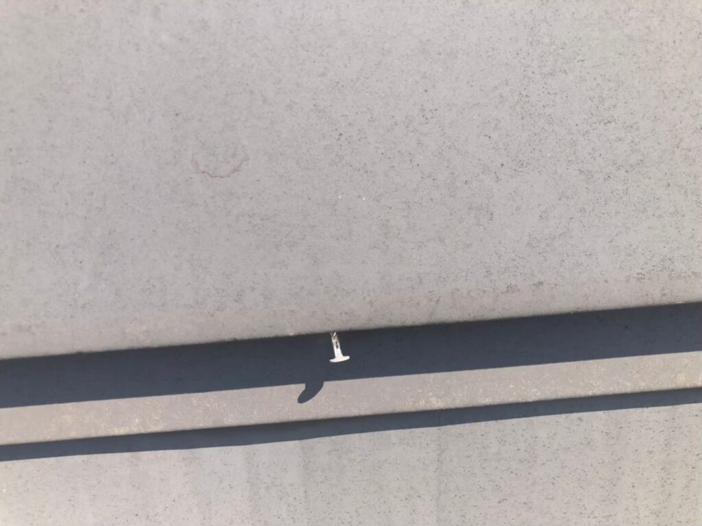 棟板金の釘が経年劣化で浮き、固定力が弱まっている状態