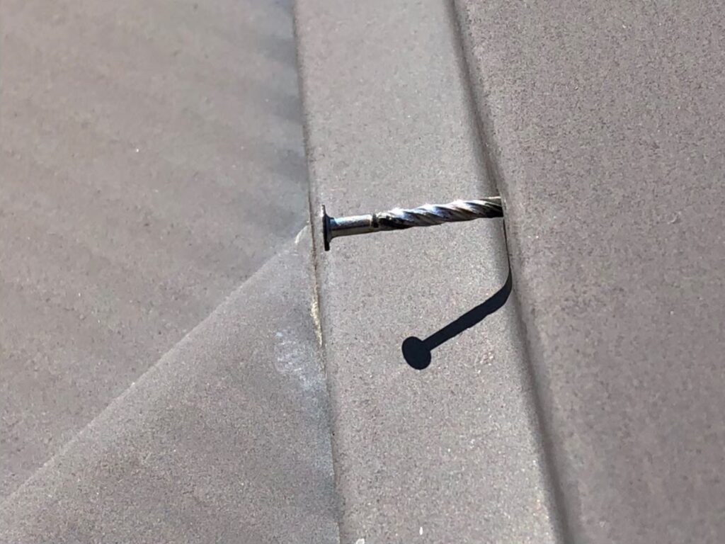 棟板金の釘が経年劣化で浮き、固定力が弱まっている状態