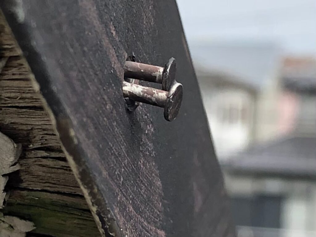 棟板金の釘が経年劣化で浮き、固定力が弱まっている状態