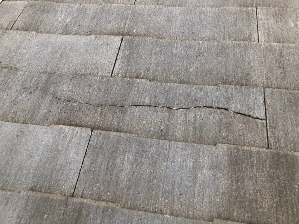 台風の影響によりスレート屋根にひび割れが生じた状態。