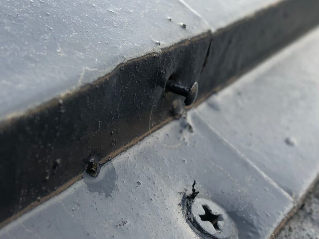 棟板金の釘が経年劣化で浮き、固定力が弱まっている状態