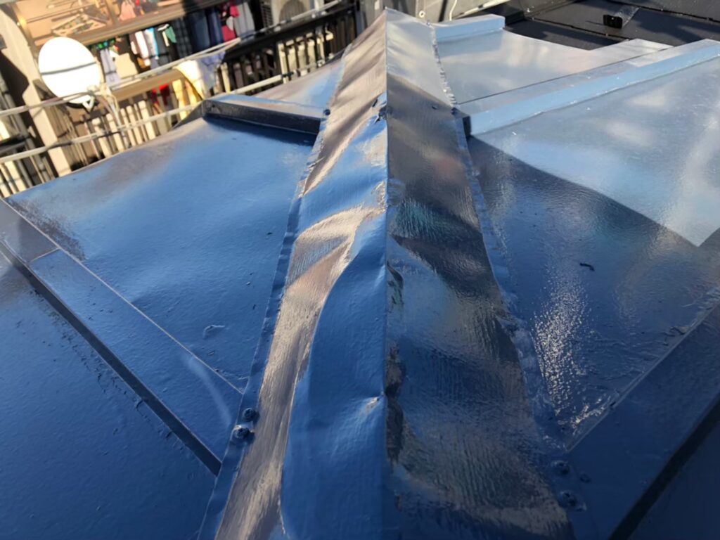 棟板金が強風や飛来物の衝撃でへこみ、形状が変わってしまっている様子