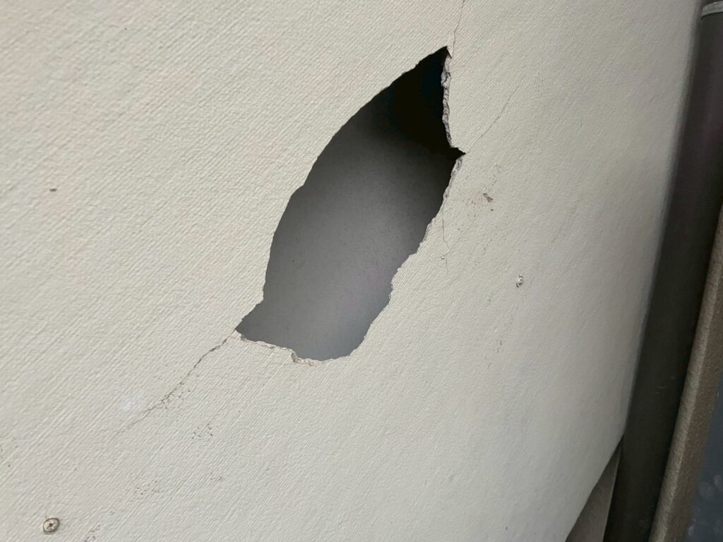 突発的な衝突により外壁に穴が空いている状態