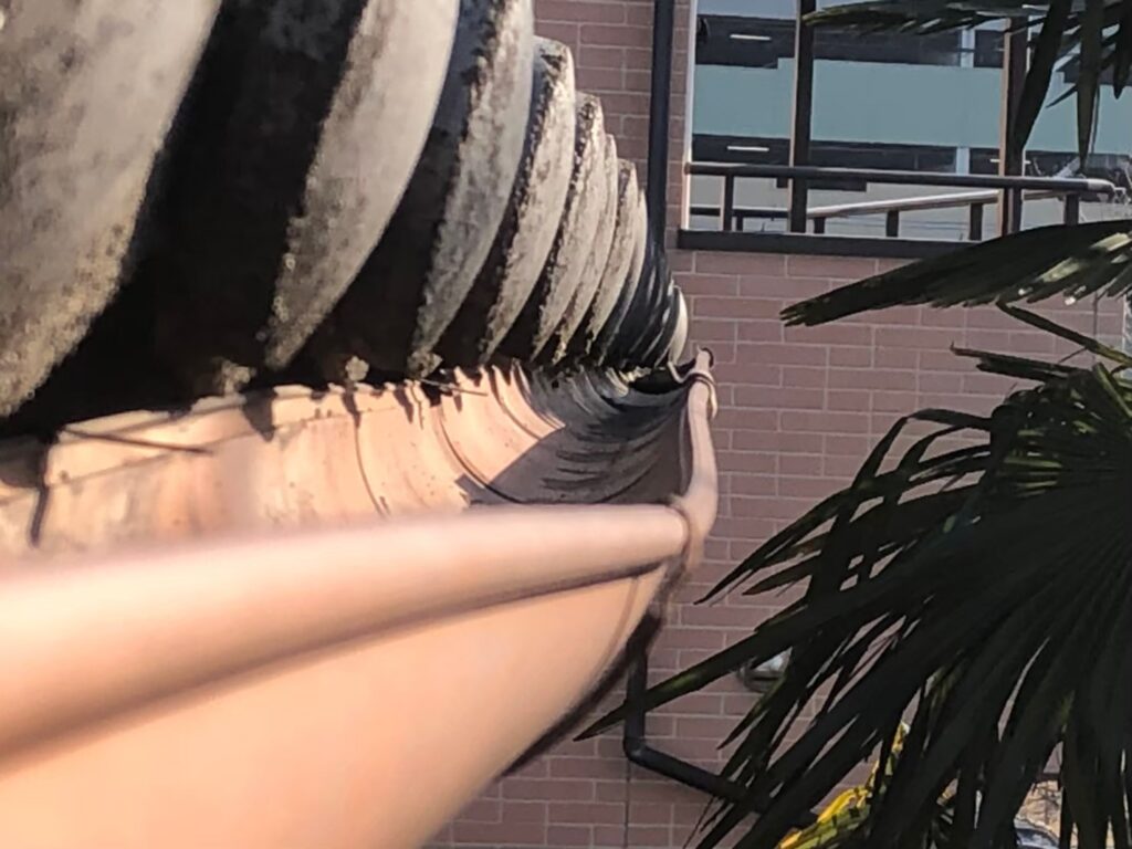 強風の影響により雨樋が大きく歪んでいる状態