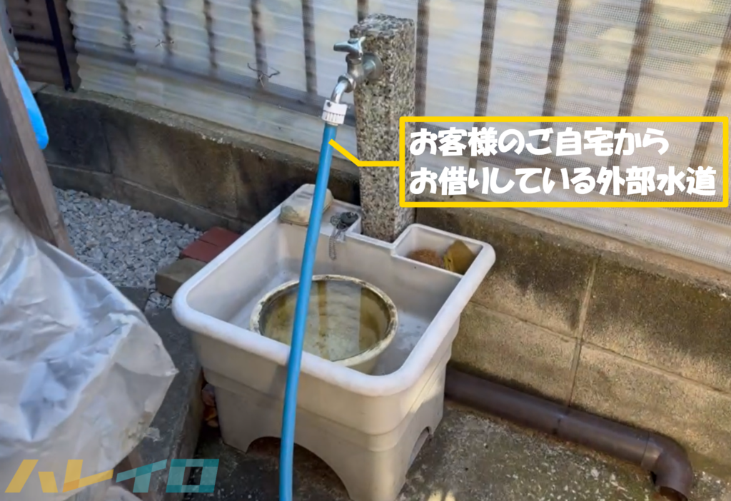 お客様のご自宅から借りている外部水道にホースをつなげている写真