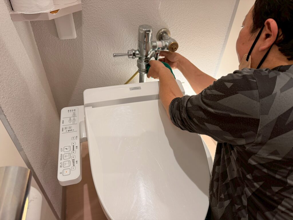 丸山建設株式会社の設備担当の職人さんが、トイレの止水栓を閉めている写真