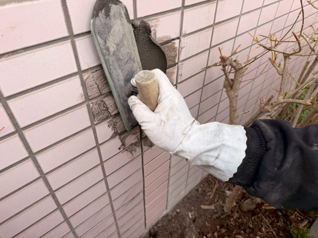 新しく貼り替えた外壁タイルの目地に、専用の目地材を均一に充填している写真