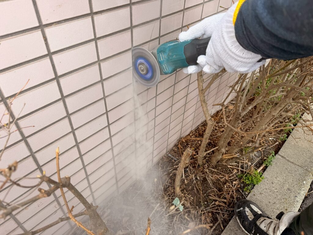 マキタのサンダーを使用して、ひび割れている外壁タイルの目地部分をカットしている写真