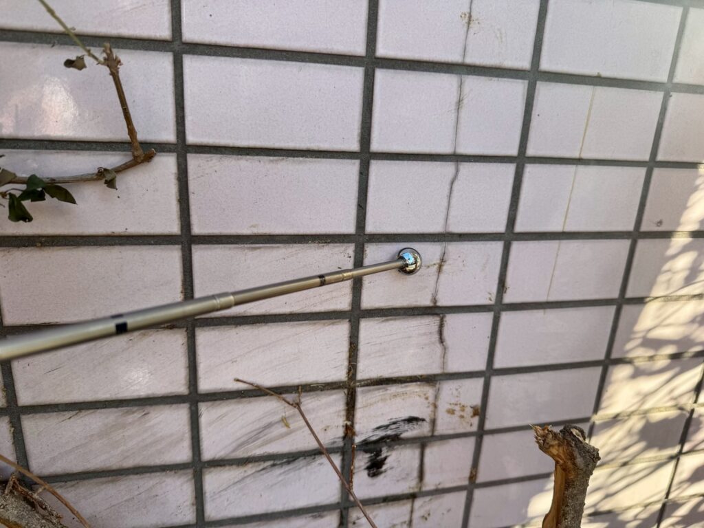 打診棒を使って外壁タイルの浮き調査をしている写真