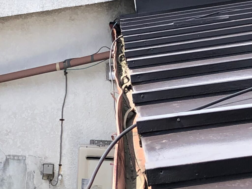 強風の影響により雨樋が大きく歪んでいる状態