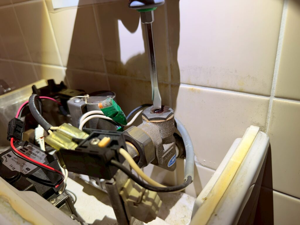 マイナスドライバーで電磁弁に設けられている止水栓を回して、止水している写真