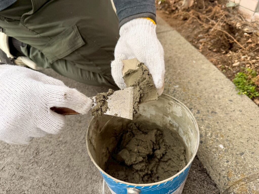 新しい外壁タイルの裏側にNSタイルセメントを充填し、下地の高さを調整している写真