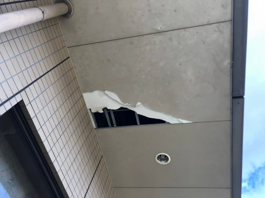 大きな穴が開き内部の木材が見えている軒天