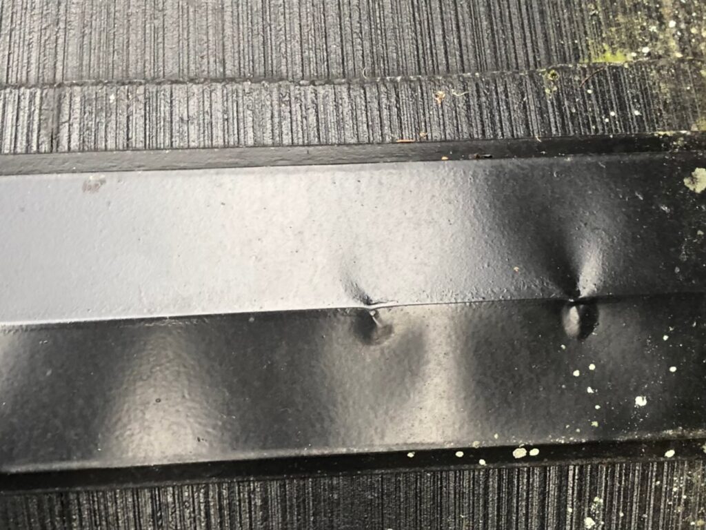 強風や飛来物の衝撃でへこんだ棟板金の変形箇所