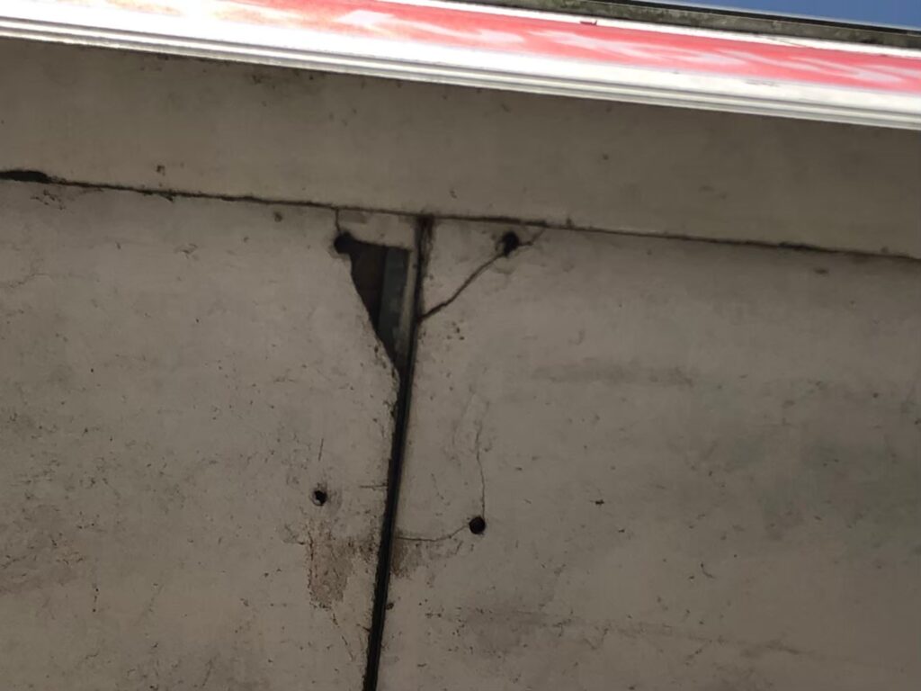 大きな穴が開き内部の木材が見えている軒天