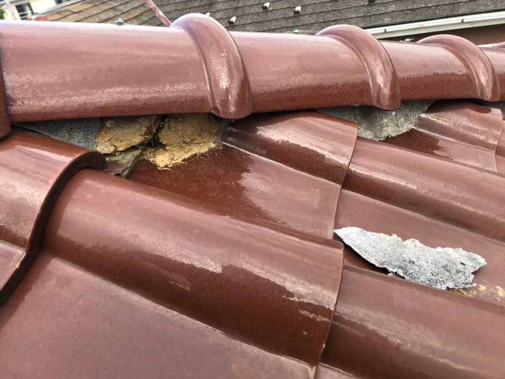 棟の漆喰が崩れて内部が露出した瓦屋根の破損状態