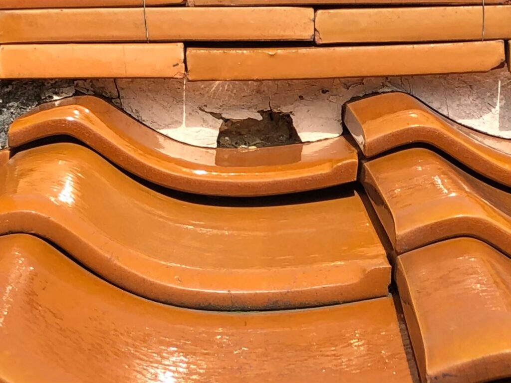 棟の漆喰が崩れて内部が露出した瓦屋根の破損状態