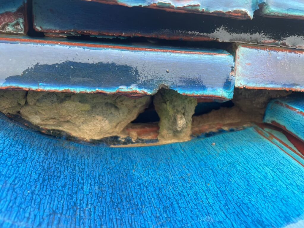 棟の漆喰が崩れて内部が露出した瓦屋根の破損状態