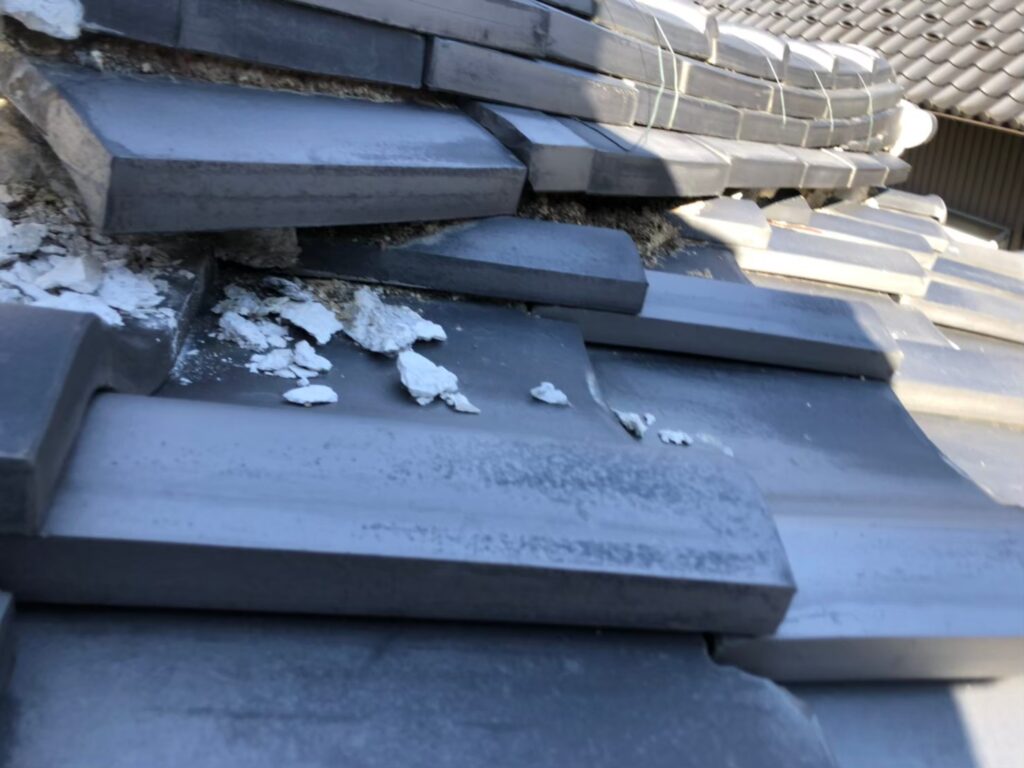 棟の漆喰が崩れて内部が露出した瓦屋根の破損状態