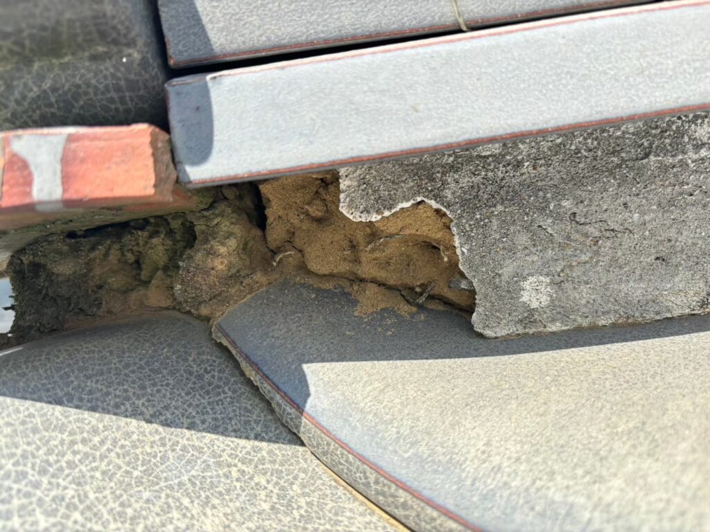 棟の漆喰が崩れて内部が露出した瓦屋根の破損状態