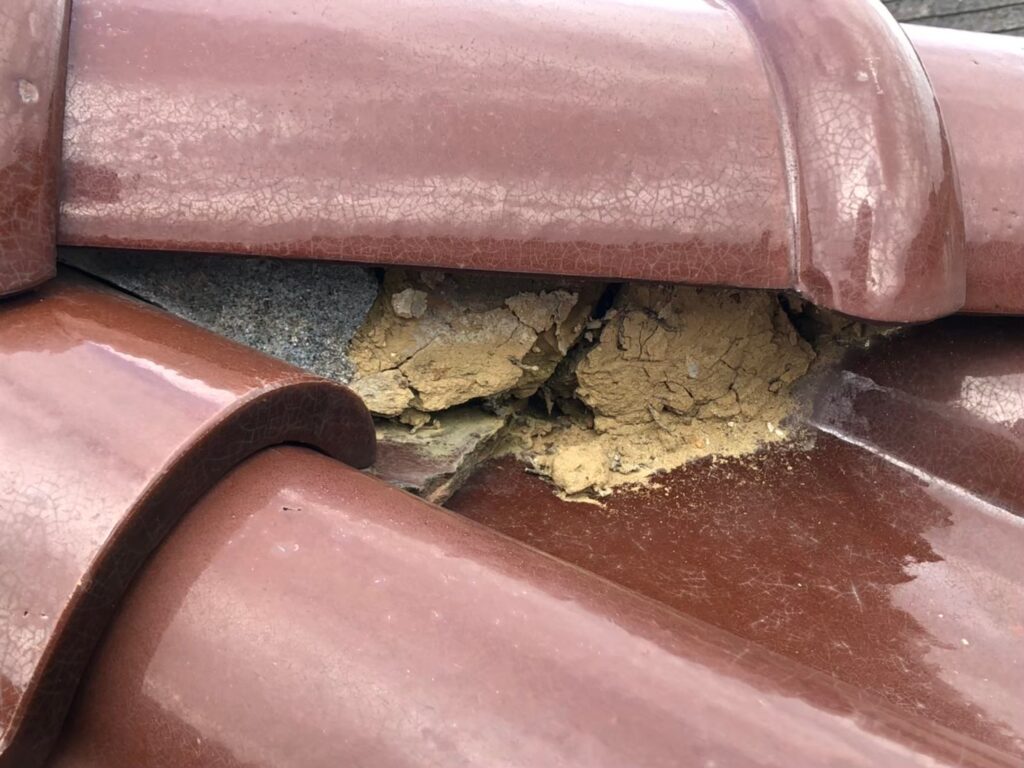 棟の漆喰が崩れて内部が露出した瓦屋根の破損状態